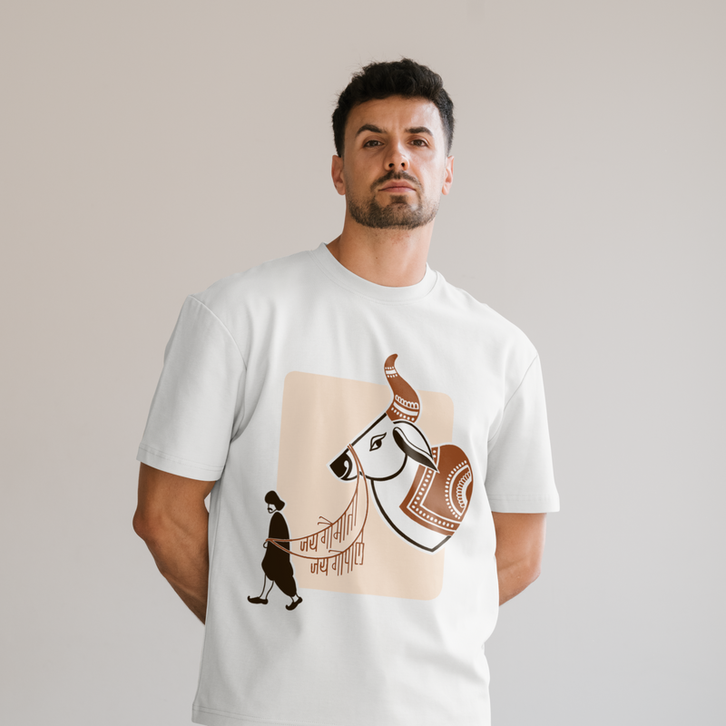 A man wearing a white crewneck t-shirt with a graphic print of a Kankrej cow and a gopal in black, set against a solid light gray background. Jai gaumata Jaigopal written in the print. 