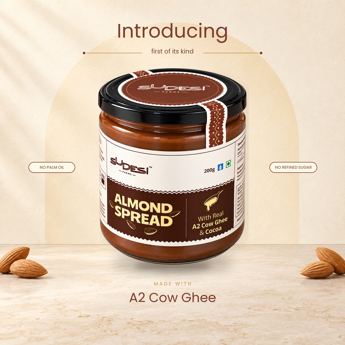 A jar of Sudesi Almond Spread with A2 Cow ghee and cocoa, presented on a light beige textured background with decorative almonds and promotional text saying " Introducing the first of its kind, made with A2 cow ghee"
