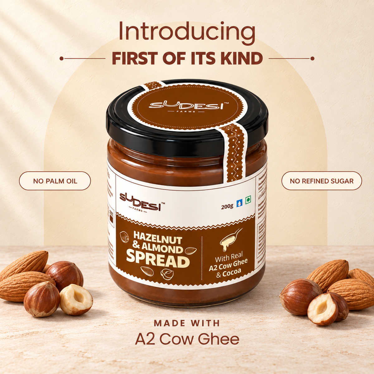 A jar of Sudesi Hazelnut & Almond Spread centered on a beige background with almonds and hazelnuts placed around it. Text above reads 'Introducing First of Its Kind' and text below reads 'Made with A2 Cow Ghee.
